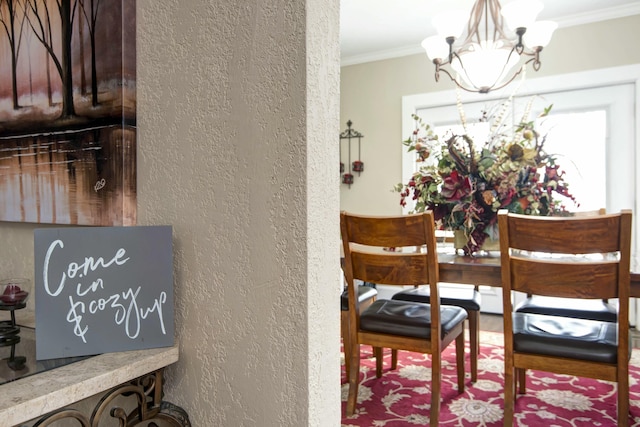 dining room with a notable chandelier, ornamental molding, and a textured wall