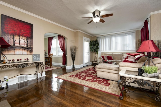 living area featuring ornamental molding, a ceiling fan, a textured ceiling, wood finished floors, and arched walkways