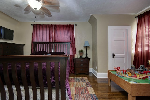 bedroom featuring baseboards, a textured ceiling, and wood finished floors