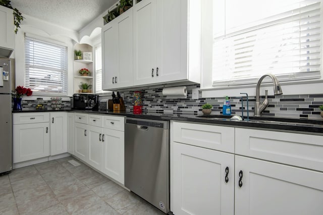 kitchen with open shelves, stainless steel appliances, dark countertops, and a sink