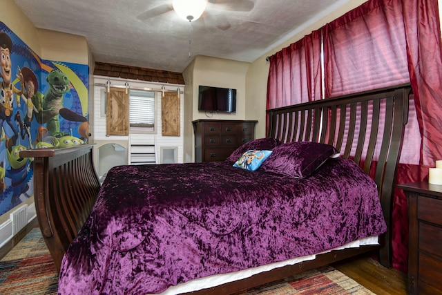 bedroom with a textured ceiling, a ceiling fan, and wood finished floors