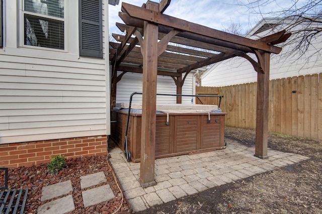 view of patio with a hot tub, a pergola, and fence