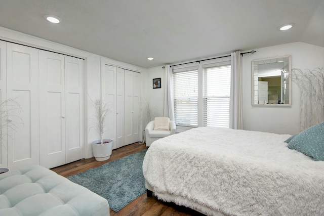 bedroom featuring dark wood-type flooring, recessed lighting, two closets, and vaulted ceiling