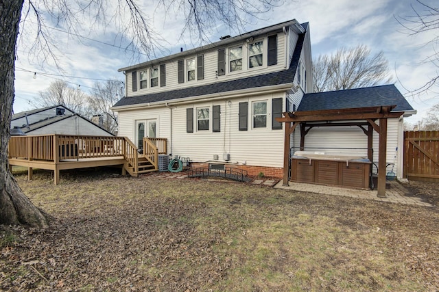 back of property featuring a shingled roof, a wooden deck, fence, and a hot tub