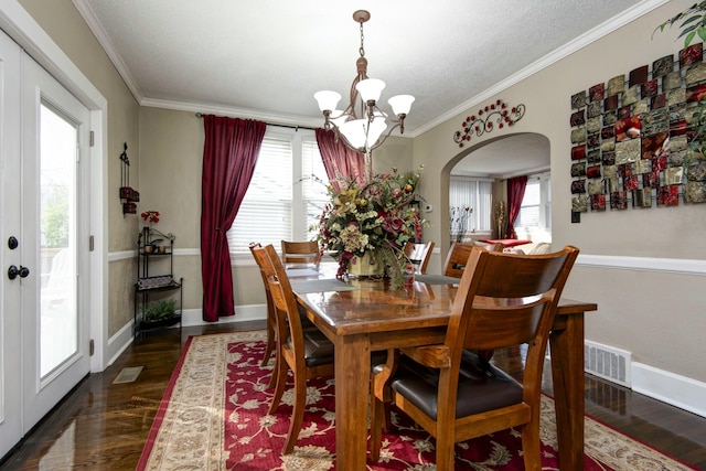 dining area with ornamental molding, arched walkways, dark wood-style flooring, and a chandelier