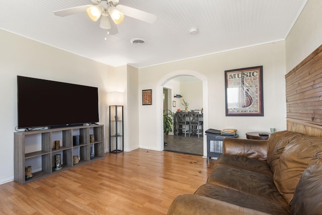 living area with arched walkways, visible vents, ceiling fan, and wood finished floors