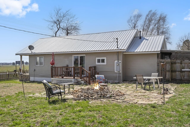 rear view of house with a deck, metal roof, fence, and an outdoor fire pit