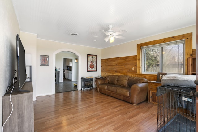 living area featuring visible vents, a ceiling fan, arched walkways, and light wood finished floors