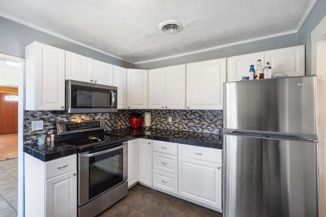 kitchen with visible vents, dark tile patterned flooring, backsplash, appliances with stainless steel finishes, and white cabinets