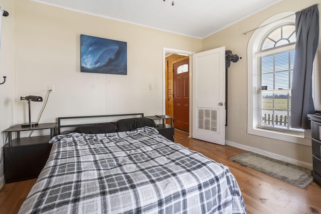 bedroom with crown molding, wood finished floors, and visible vents