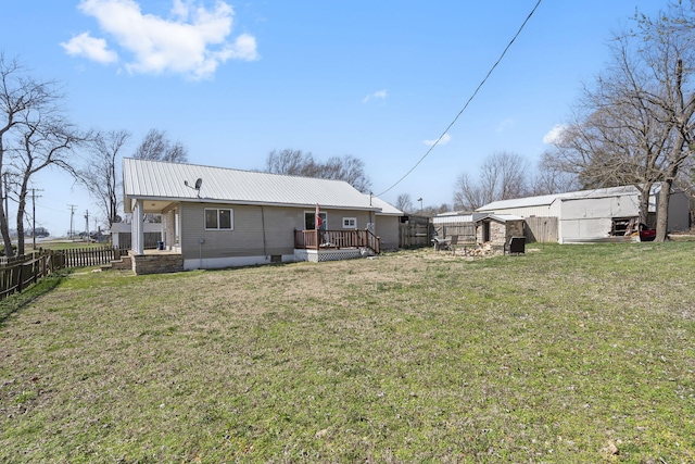 rear view of property featuring a wooden deck, metal roof, a yard, and fence