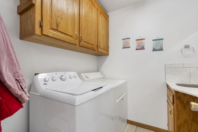 laundry room with baseboards, light tile patterned flooring, cabinet space, a sink, and washer and clothes dryer