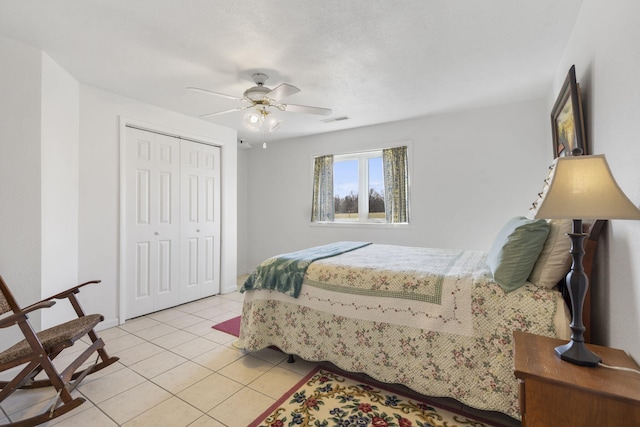 bedroom with light tile patterned floors, visible vents, a closet, and ceiling fan