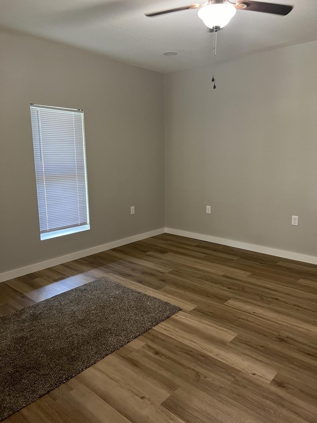 empty room featuring ceiling fan, baseboards, and wood finished floors