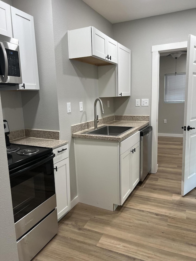 kitchen featuring a sink, light wood-style floors, white cabinetry, and stainless steel appliances