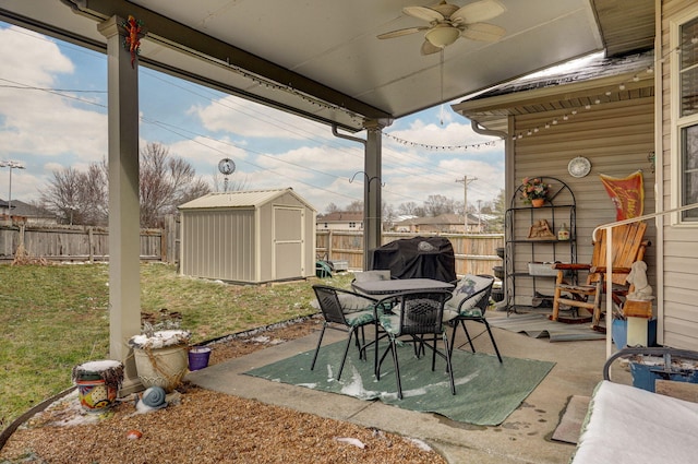 view of patio with a shed, outdoor dining area, a fenced backyard, ceiling fan, and an outdoor structure