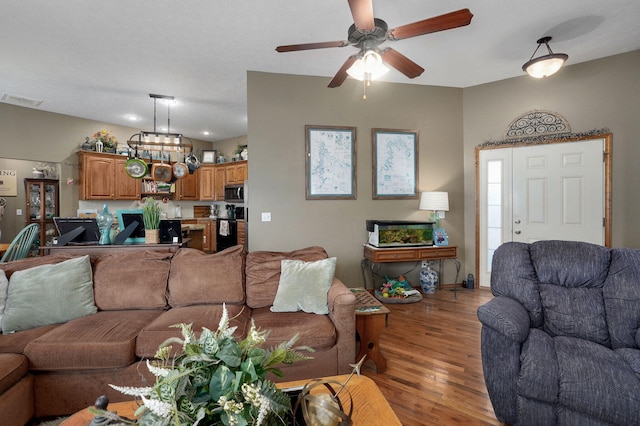 living area with light wood-style floors, visible vents, and ceiling fan