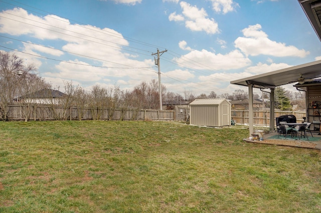 view of yard with an outbuilding, a storage shed, a fenced backyard, and a patio area