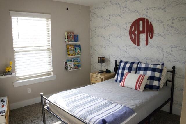 bedroom featuring multiple windows, wallpapered walls, an accent wall, and baseboards