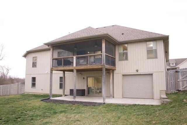 back of property featuring a shingled roof, fence, a lawn, a patio area, and an attached garage