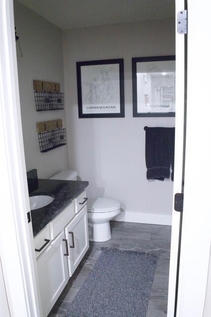 bathroom with baseboards, toilet, and vanity