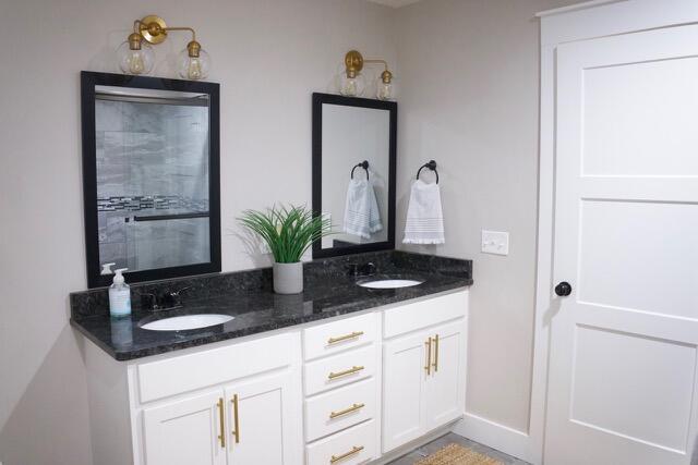 bathroom featuring double vanity, baseboards, and a sink