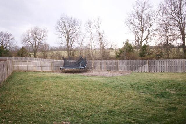 view of yard featuring a trampoline and a fenced backyard