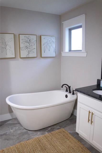 full bath featuring baseboards, a soaking tub, and vanity