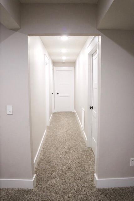 hallway with carpet flooring and baseboards