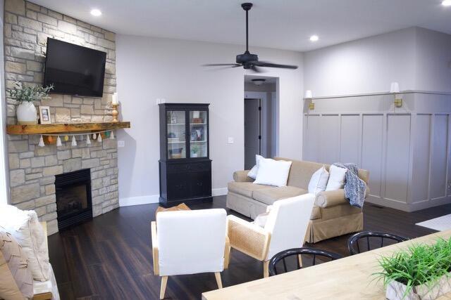 living area featuring baseboards, ceiling fan, a stone fireplace, recessed lighting, and wood finished floors