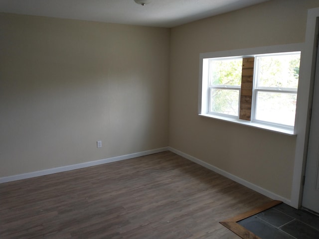 unfurnished room featuring baseboards and dark wood-type flooring