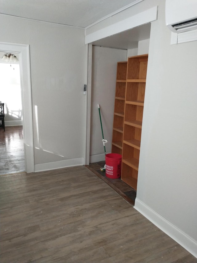 interior space featuring a wall unit AC, wood finished floors, and baseboards