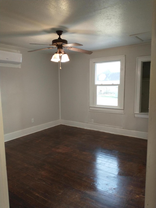 unfurnished room with a wall mounted air conditioner, baseboards, dark wood-style floors, and a ceiling fan