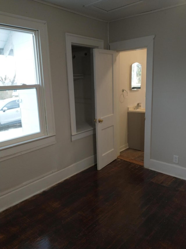 unfurnished bedroom with multiple windows, baseboards, and wood finished floors