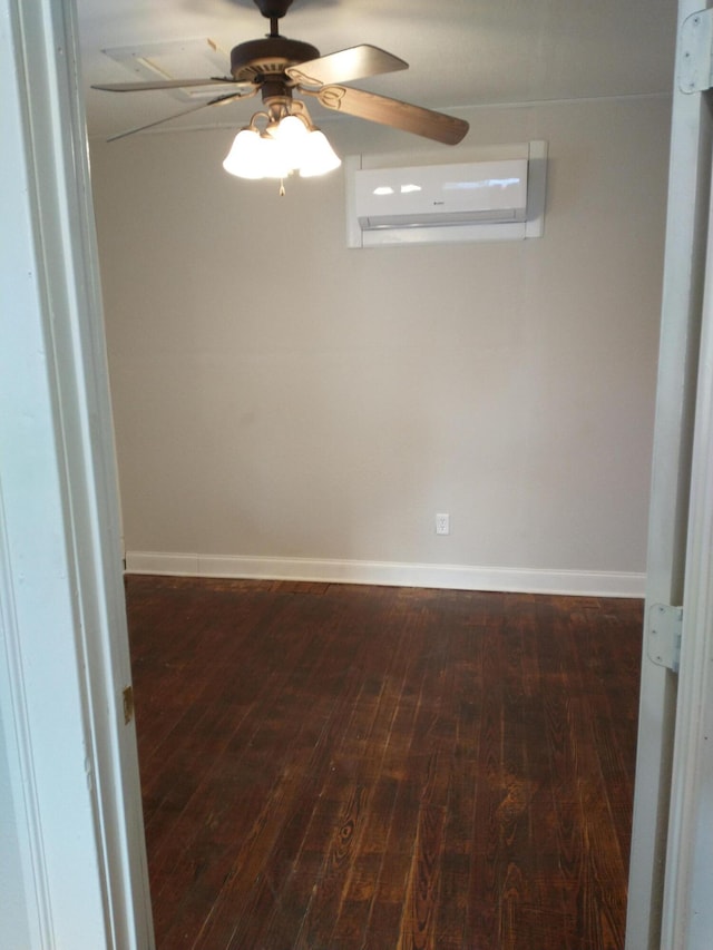 unfurnished room with an AC wall unit, baseboards, wood-type flooring, and ceiling fan