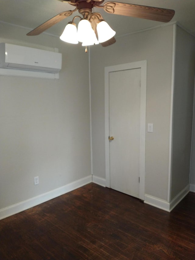 spare room featuring baseboards, wood finished floors, a ceiling fan, and a wall unit AC