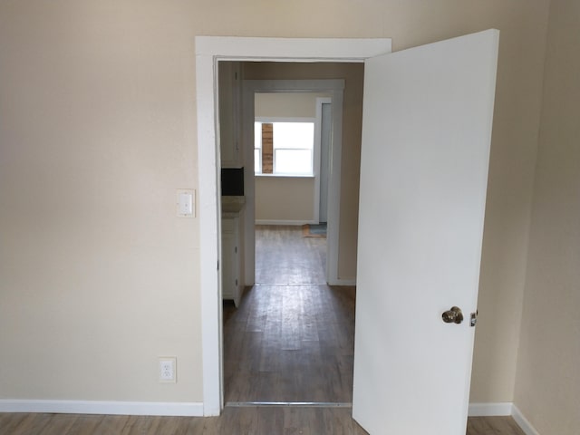 corridor featuring wood finished floors and baseboards