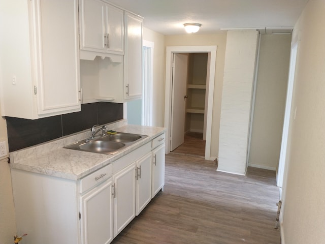 kitchen with white cabinetry, light countertops, light wood-style floors, and a sink