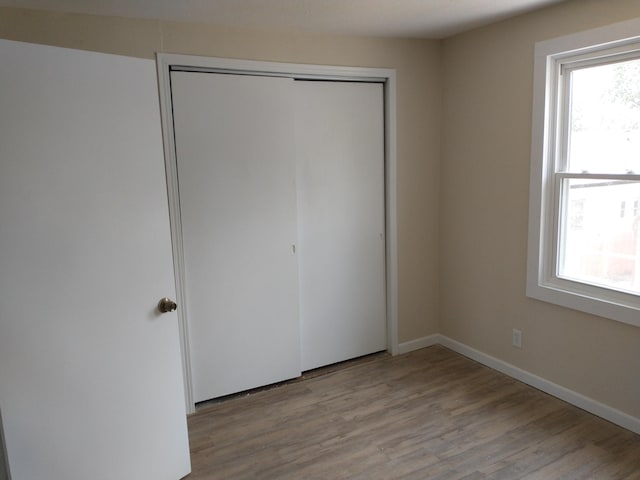 unfurnished bedroom with a closet, multiple windows, and wood finished floors