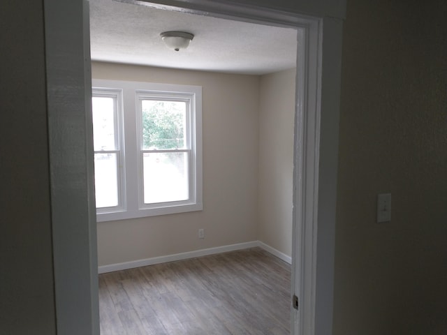 spare room featuring baseboards and wood finished floors