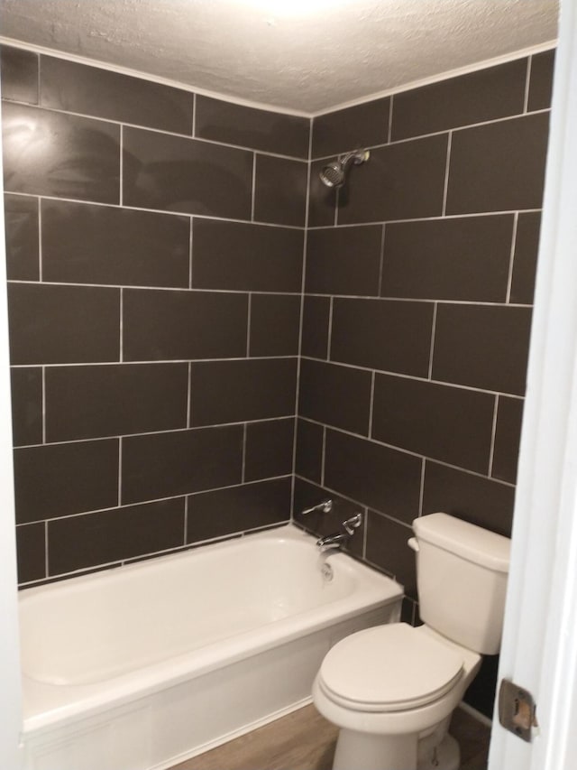 full bathroom featuring a textured ceiling, toilet, and  shower combination