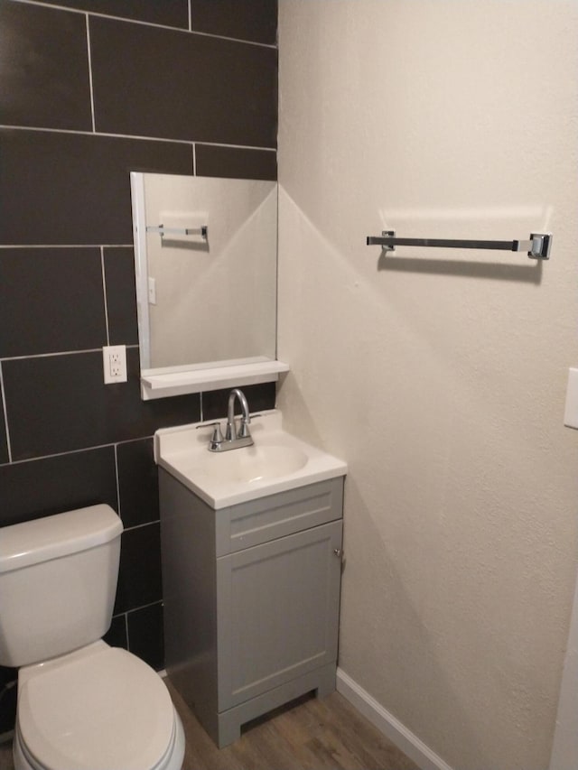 bathroom featuring toilet, wood finished floors, tile walls, baseboards, and vanity