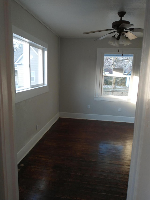 spare room with dark wood-style floors, baseboards, and a ceiling fan