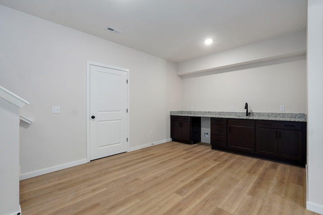 bar with indoor wet bar, visible vents, baseboards, and light wood-style floors