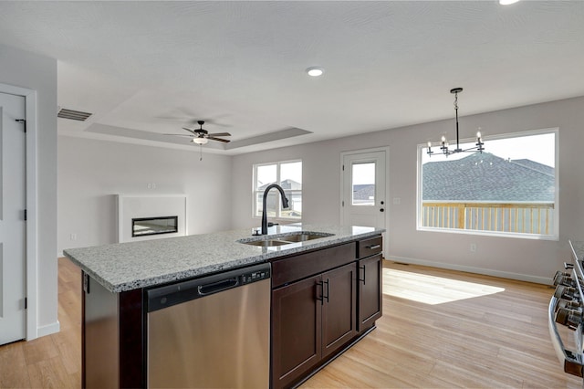 kitchen featuring light wood finished floors, a sink, dark brown cabinets, dishwasher, and a raised ceiling