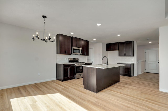 kitchen featuring a sink, dark brown cabinets, appliances with stainless steel finishes, a notable chandelier, and tasteful backsplash