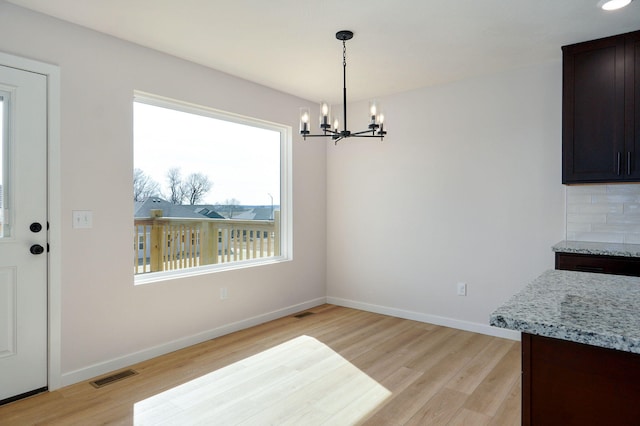 dining area with an inviting chandelier, light wood-style flooring, baseboards, and visible vents