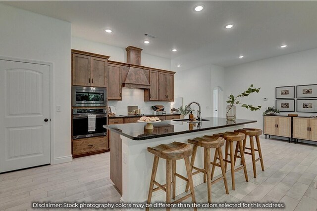 5202 S April Ct, Battlefield, MO 65619 - kitchen with a center island with sink, custom exhaust hood, a sink, stainless steel appliances, and a kitchen breakfast bar