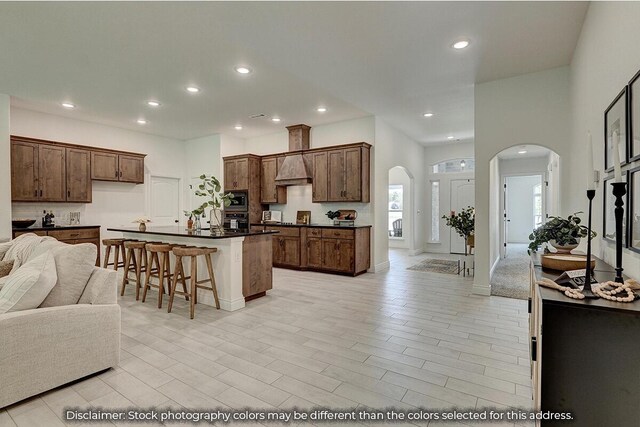 5202 S April Ct, Battlefield, MO 65619 - kitchen with arched walkways, custom range hood, dark countertops, a kitchen breakfast bar, and open floor plan