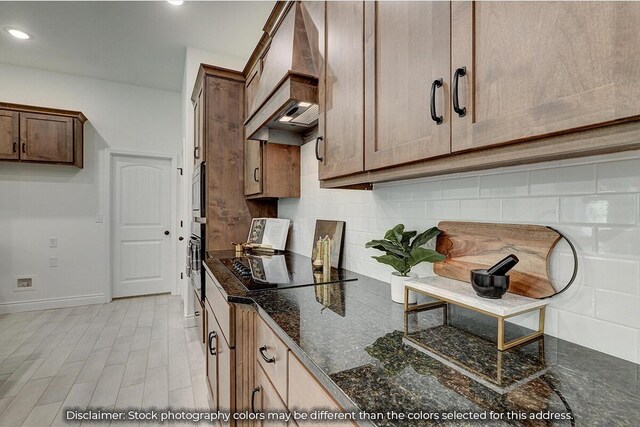 5202 S April Ct, Battlefield, MO 65619 - kitchen with tasteful backsplash, baseboards, black electric stovetop, dark stone countertops, and custom exhaust hood
